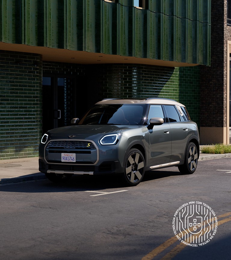 MINI Countryman visto de frente e de lado, estacionado numa rua junto a um edifício  verde